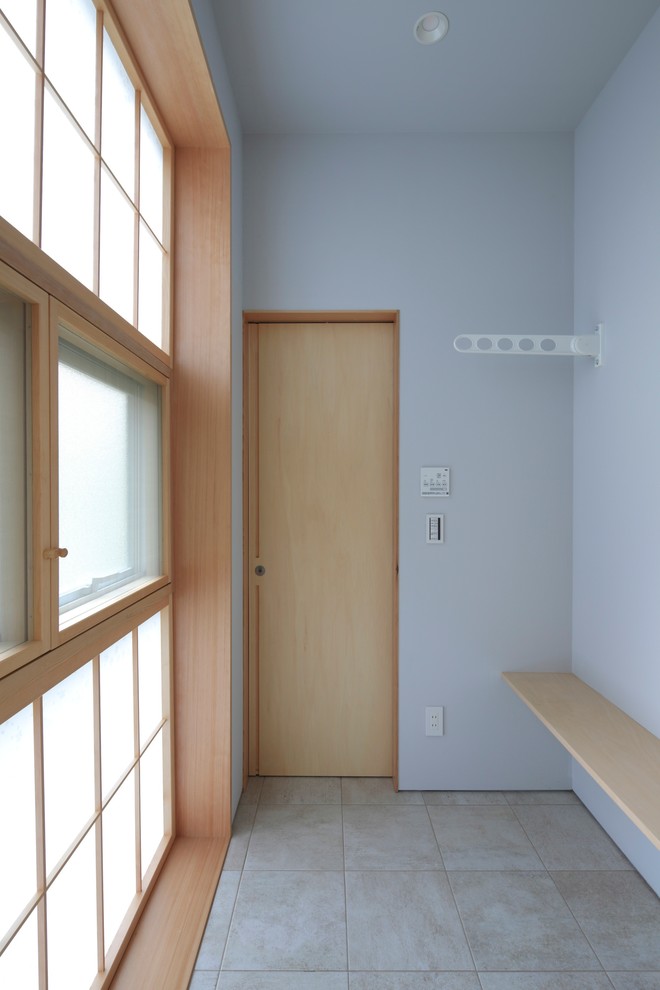 This is an example of a small asian single-wall utility room in Tokyo with open cabinets, light wood cabinets, wood benchtops, white walls, ceramic floors, a side-by-side washer and dryer and grey floor.