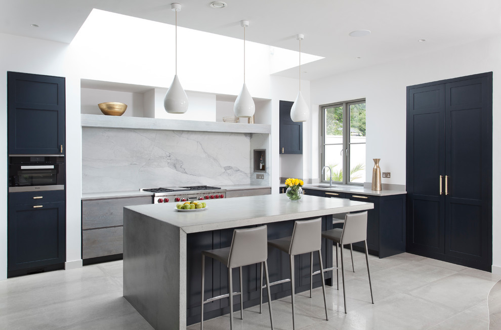 This is an example of a transitional kitchen in Dublin with an undermount sink, stainless steel appliances, with island, grey floor, concrete benchtops, concrete floors, white splashback and marble splashback.