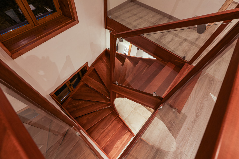 Inspiration för stora moderna svängda trappor i trä, med öppna sättsteg och räcke i glas