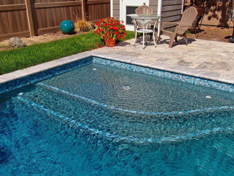Small traditional backyard rectangular pool in Other with natural stone pavers.