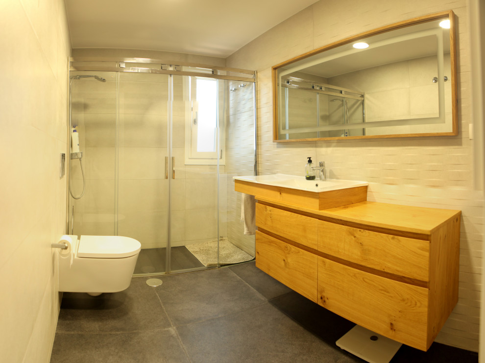 This is an example of a mid-sized mediterranean 3/4 bathroom in Alicante-Costa Blanca with medium wood cabinets, a curbless shower, white tile, ceramic tile, white walls, ceramic floors, a vessel sink, wood benchtops, grey floor, a sliding shower screen, an enclosed toilet, a single vanity and a floating vanity.