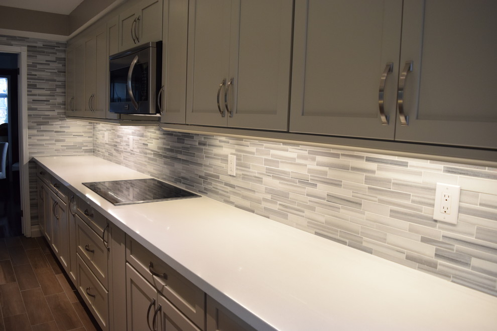 Inspiration for a mid-sized transitional l-shaped eat-in kitchen remodel in Toronto with an undermount sink, shaker cabinets, gray cabinets, quartzite countertops, multicolored backsplash, subway tile backsplash, stainless steel appliances and an island