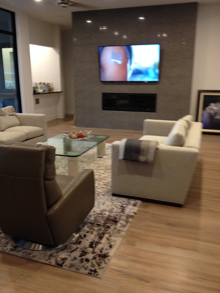 This is an example of a large modern open concept family room in Houston with grey walls, porcelain floors, a ribbon fireplace, a tile fireplace surround and a wall-mounted tv.