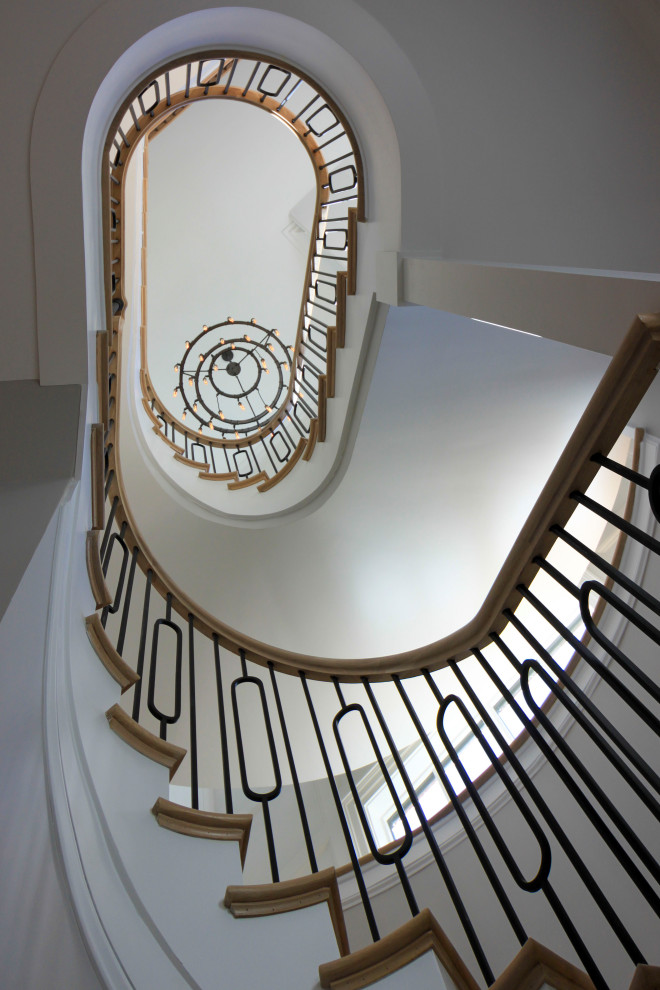 Réalisation d'un très grand escalier courbe tradition avec des marches en bois, des contremarches en bois, un garde-corps en matériaux mixtes et boiseries.