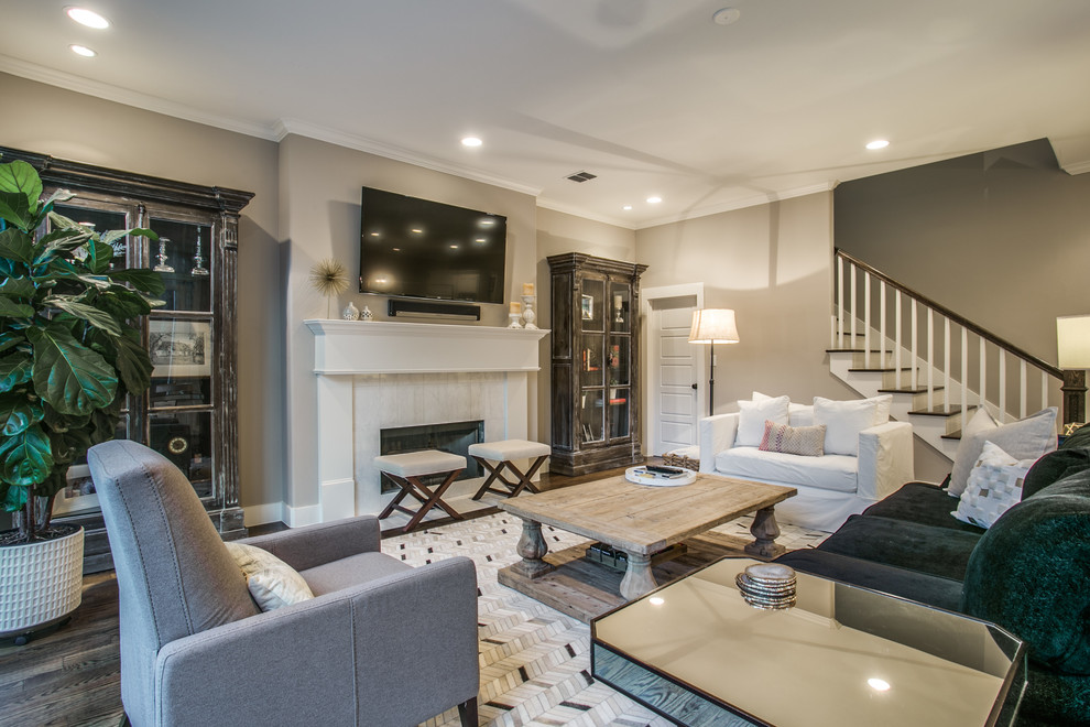 This is an example of a large contemporary formal open concept living room in Dallas with beige walls, medium hardwood floors, a standard fireplace, a wood fireplace surround, a wall-mounted tv and brown floor.