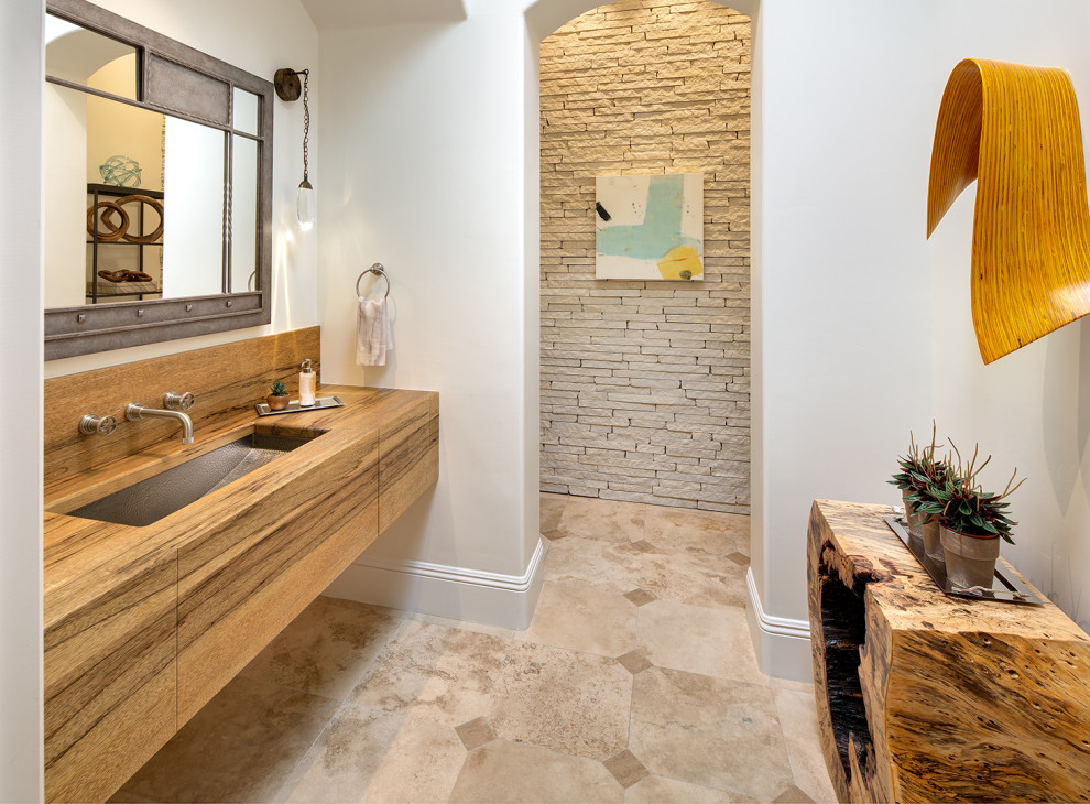 Inspiration for a mid-sized transitional bathroom in San Diego with flat-panel cabinets, medium wood cabinets, a one-piece toilet, white tile, limestone, white walls, travertine floors, an undermount sink, wood benchtops, beige floor, an enclosed toilet, a single vanity and a floating vanity.