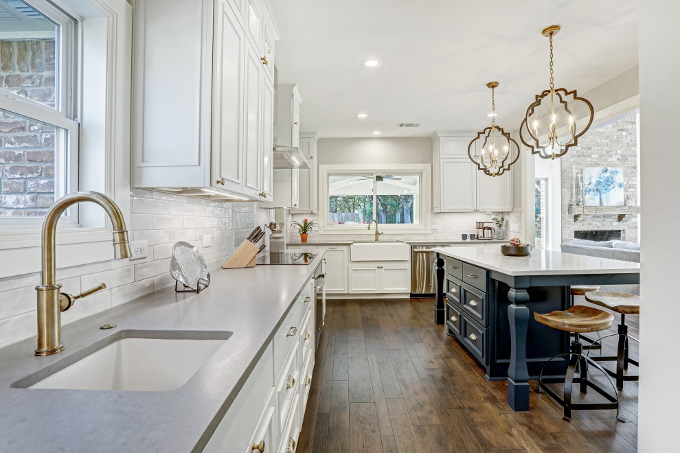 Photo of a mid-sized country u-shaped eat-in kitchen in Austin with an undermount sink, recessed-panel cabinets, white cabinets, quartz benchtops, white splashback, porcelain splashback, stainless steel appliances, dark hardwood floors, with island, brown floor and white benchtop.