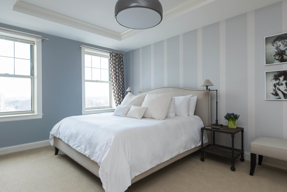 This is an example of a large contemporary master bedroom in New York with blue walls and carpet.