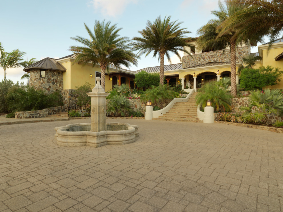 Expansive mediterranean two-storey yellow exterior in Other with stone veneer and a hip roof.