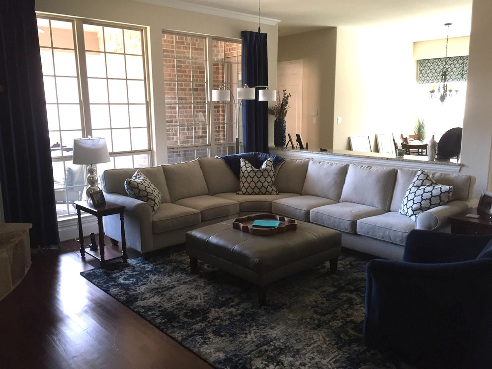 Inspiration for a mid-sized transitional open concept family room in Dallas with beige walls, dark hardwood floors, a hanging fireplace, a stone fireplace surround, a wall-mounted tv and brown floor.