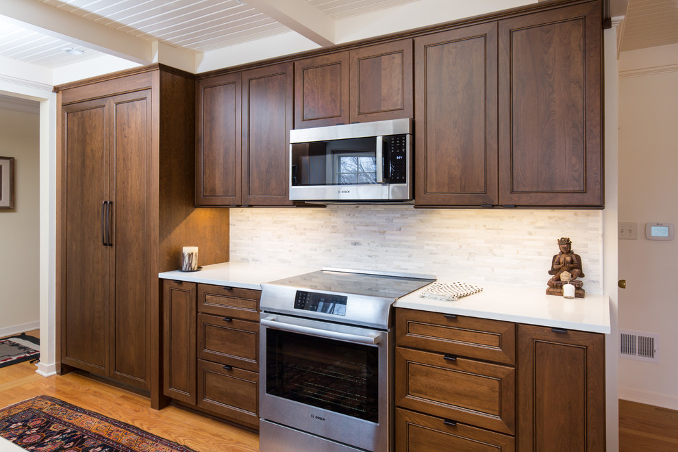 Foto de cocina comedor clásica renovada pequeña sin isla con fregadero bajoencimera, armarios estilo shaker, puertas de armario de madera en tonos medios, encimera de cuarzo compacto, salpicadero blanco, salpicadero con mosaicos de azulejos, electrodomésticos de acero inoxidable, suelo de madera en tonos medios y encimeras blancas