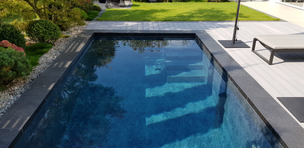 Small mediterranean side yard rectangular pool in Frankfurt with natural stone pavers.