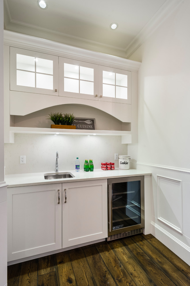 Example of a huge mountain style u-shaped medium tone wood floor and brown floor open concept kitchen design in Vancouver with an undermount sink, shaker cabinets, white cabinets, solid surface countertops, white backsplash, stone slab backsplash, stainless steel appliances, an island and white countertops