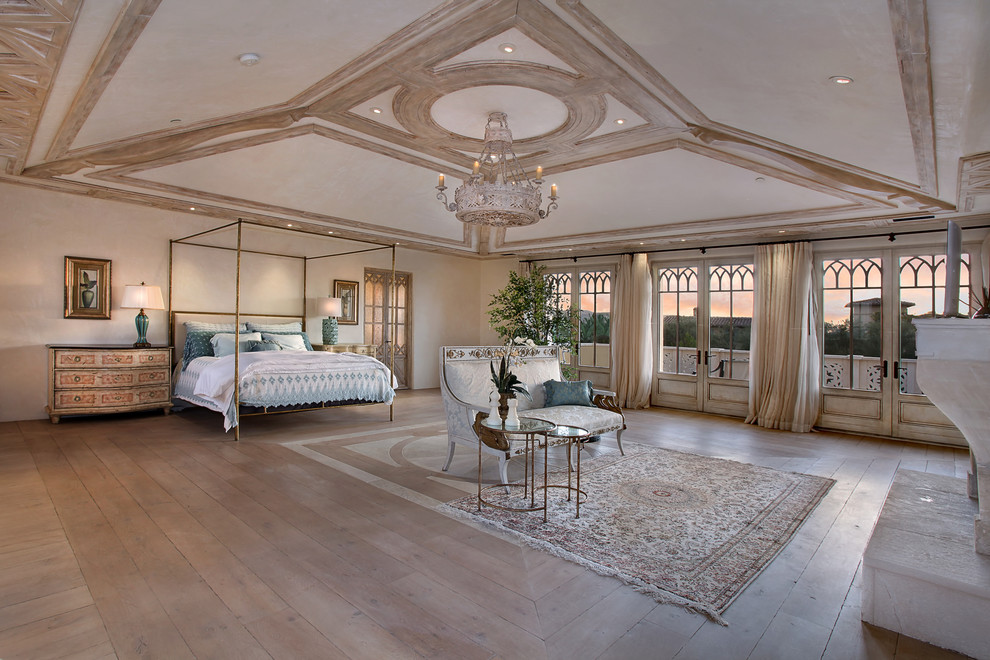 Design ideas for a mediterranean master bedroom in Orange County with beige walls, light hardwood floors and a standard fireplace.