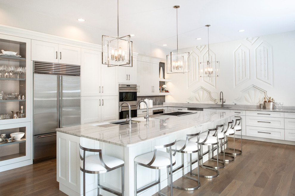 Open concept kitchen - large transitional medium tone wood floor and brown floor open concept kitchen idea with an undermount sink, recessed-panel cabinets, white cabinets, quartzite countertops, brown backsplash, ceramic backsplash, stainless steel appliances, an island and white countertops