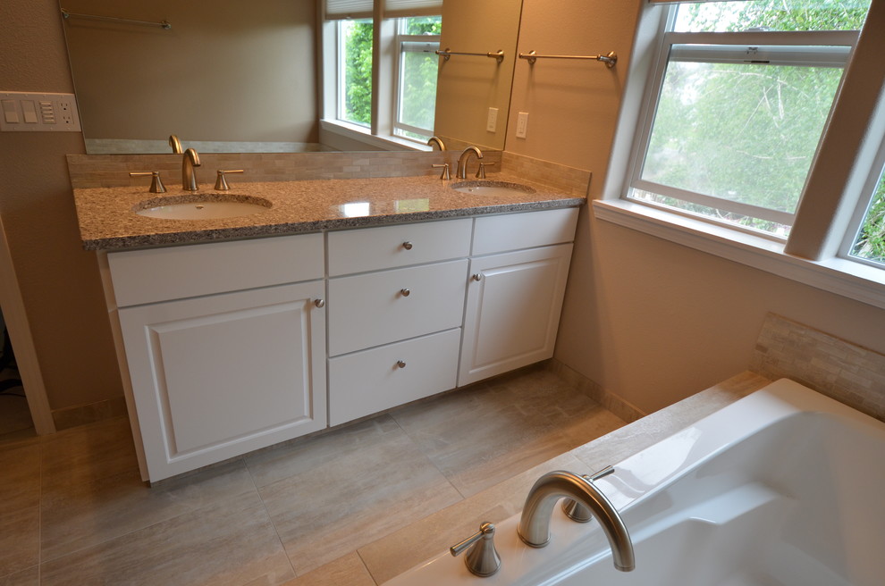 Mid-sized transitional master bathroom in Portland with an undermount sink, flat-panel cabinets, white cabinets, solid surface benchtops, a drop-in tub, an alcove shower, beige tile, porcelain tile, beige walls and porcelain floors.