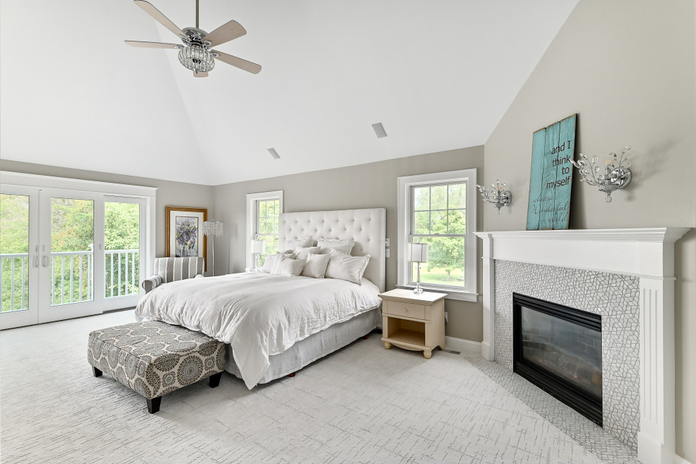 Photo of an expansive transitional master bedroom in Milwaukee with beige walls, carpet, a standard fireplace, a tile fireplace surround, white floor and vaulted.