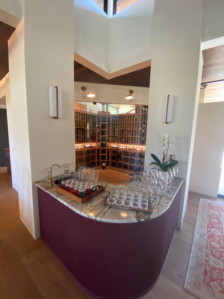 Cette photo montre une cave à vin moderne de taille moyenne avec parquet clair, des casiers et un sol multicolore.