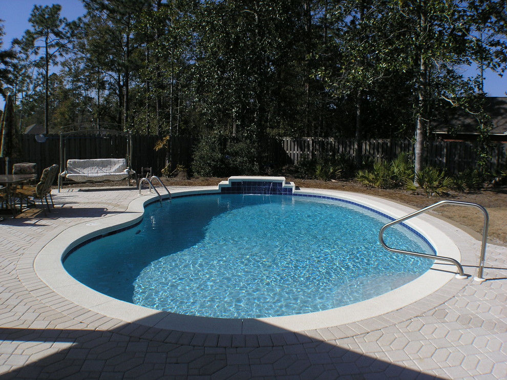 Mid-sized tropical backyard kidney-shaped natural pool in Miami with concrete pavers.