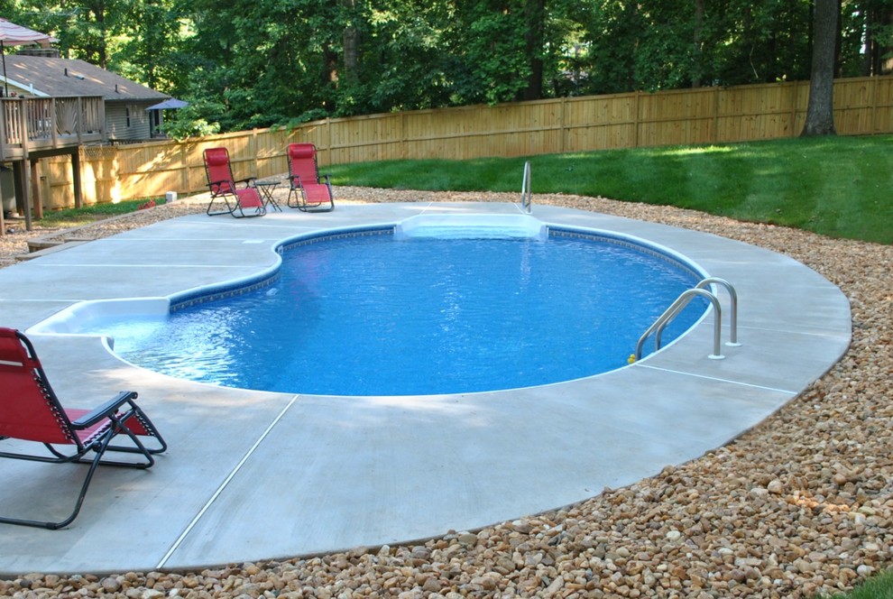 Photo of a mid-sized traditional backyard kidney-shaped pool in DC Metro with concrete slab.