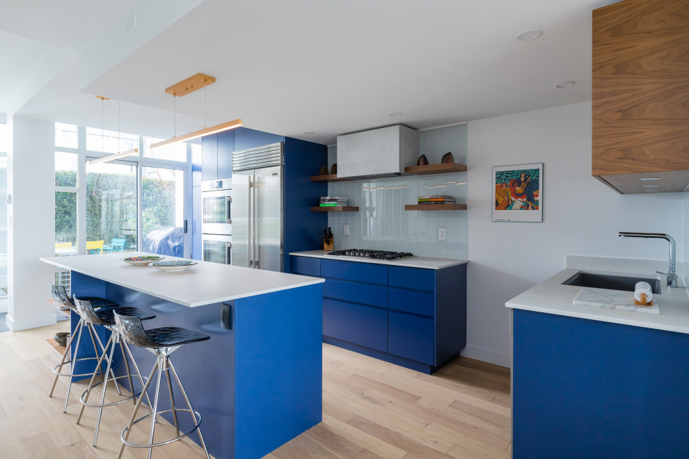 Inspiration for a large modern l-shaped eat-in kitchen in Vancouver with an undermount sink, flat-panel cabinets, blue cabinets, quartzite benchtops, blue splashback, subway tile splashback, stainless steel appliances, vinyl floors, with island, beige floor and white benchtop.
