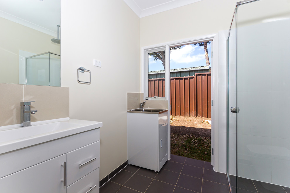 Small contemporary bathroom in Sydney with a wall-mount sink, flat-panel cabinets, white cabinets, solid surface benchtops, a corner shower, a one-piece toilet, black tile, ceramic tile, white walls and ceramic floors.