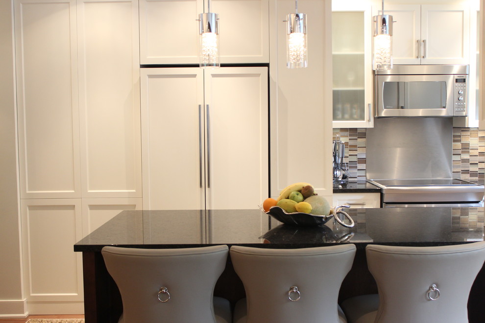 This is an example of a mid-sized contemporary u-shaped separate kitchen in Montreal with an undermount sink, recessed-panel cabinets, white cabinets, granite benchtops, beige splashback, matchstick tile splashback, stainless steel appliances, medium hardwood floors, a peninsula and brown floor.