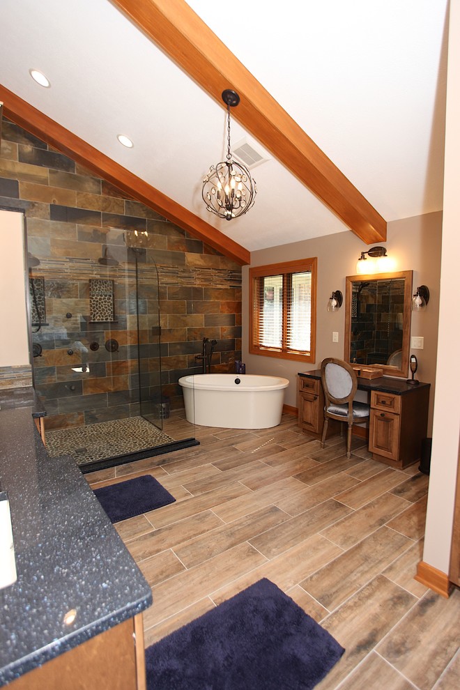 Example of a large mountain style master slate tile brown floor freestanding bathtub design in Indianapolis with brown cabinets, beige walls and an undermount sink