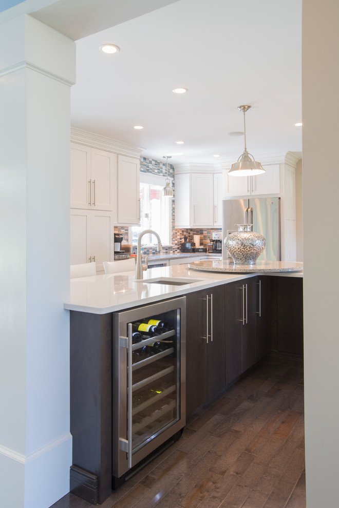 Example of a large trendy u-shaped dark wood floor and brown floor eat-in kitchen design with an undermount sink, recessed-panel cabinets, dark wood cabinets, quartz countertops, multicolored backsplash, matchstick tile backsplash, stainless steel appliances, two islands and white countertops