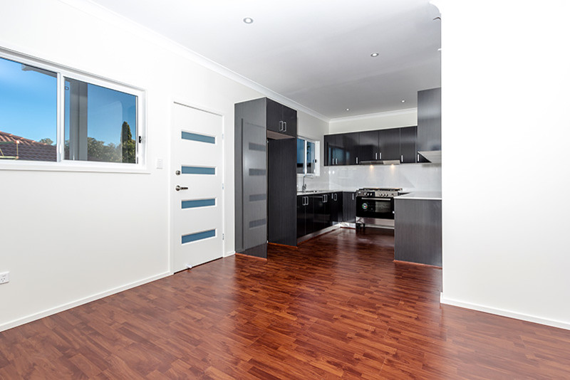 Inspiration for a mid-sized contemporary u-shaped kitchen pantry with a drop-in sink, flat-panel cabinets, dark wood cabinets, laminate benchtops, white splashback, ceramic splashback, stainless steel appliances, white walls, laminate floors and no island.