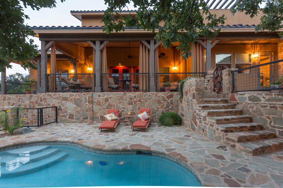 Photo of a large backyard custom-shaped pool in Austin with natural stone pavers.
