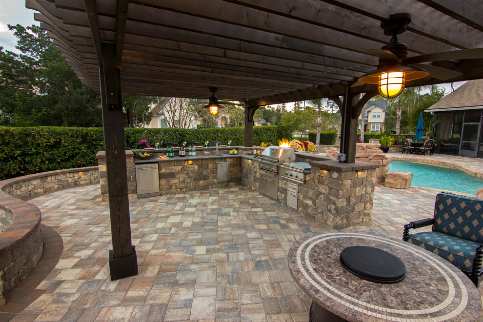 Large traditional backyard patio in Jacksonville with an outdoor kitchen, natural stone pavers and a pergola.