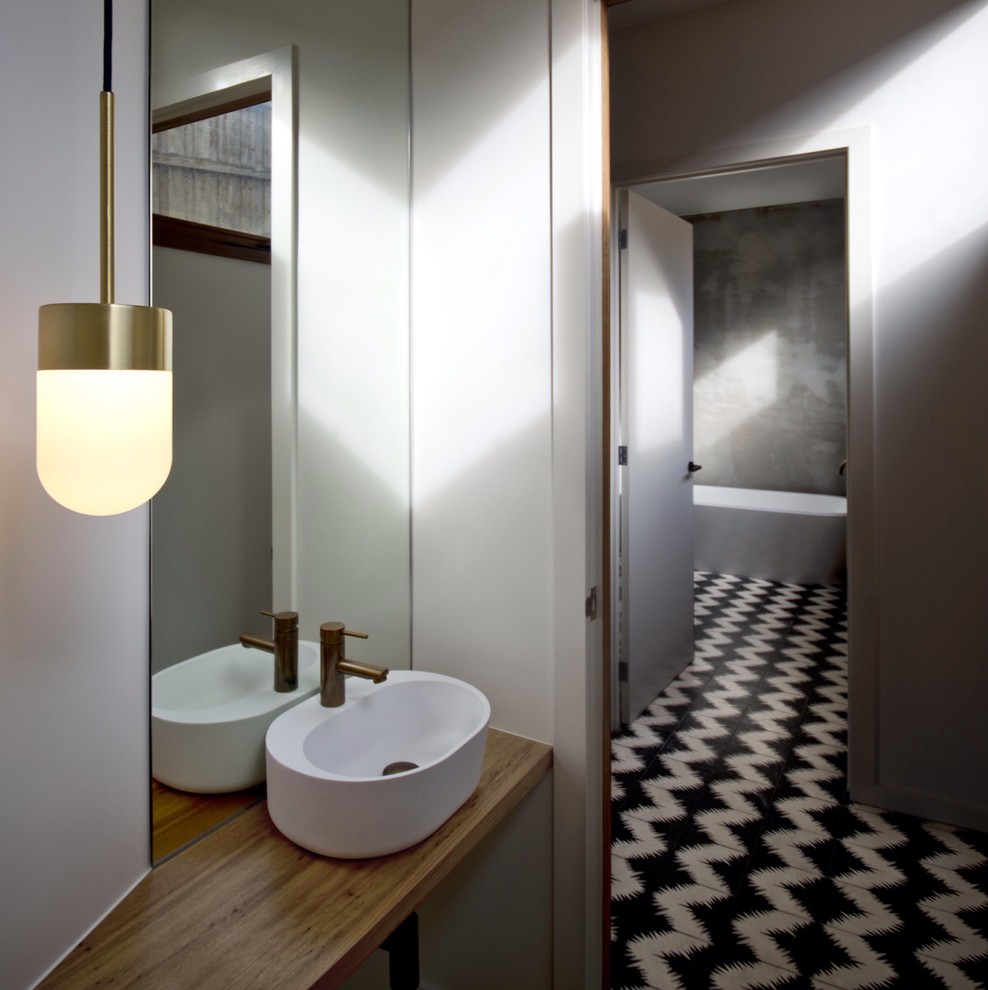 This is an example of a contemporary bathroom in Melbourne with a vessel sink, medium wood cabinets, wood benchtops, a one-piece toilet and white walls.