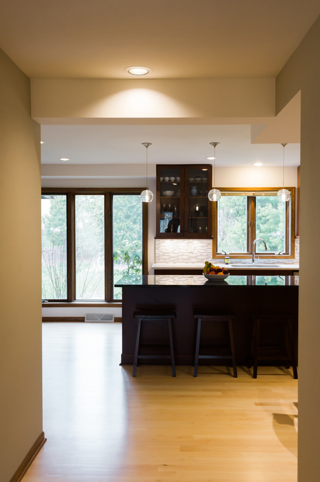 Eat-in kitchen - large transitional l-shaped light wood floor eat-in kitchen idea with an undermount sink, shaker cabinets, dark wood cabinets, quartz countertops, gray backsplash, matchstick tile backsplash, stainless steel appliances and an island