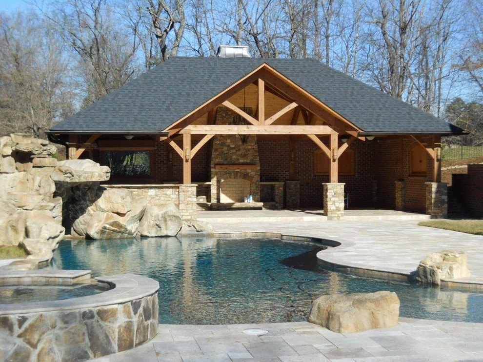 This is an example of a mid-sized country backyard custom-shaped pool in Charlotte with a hot tub and natural stone pavers.
