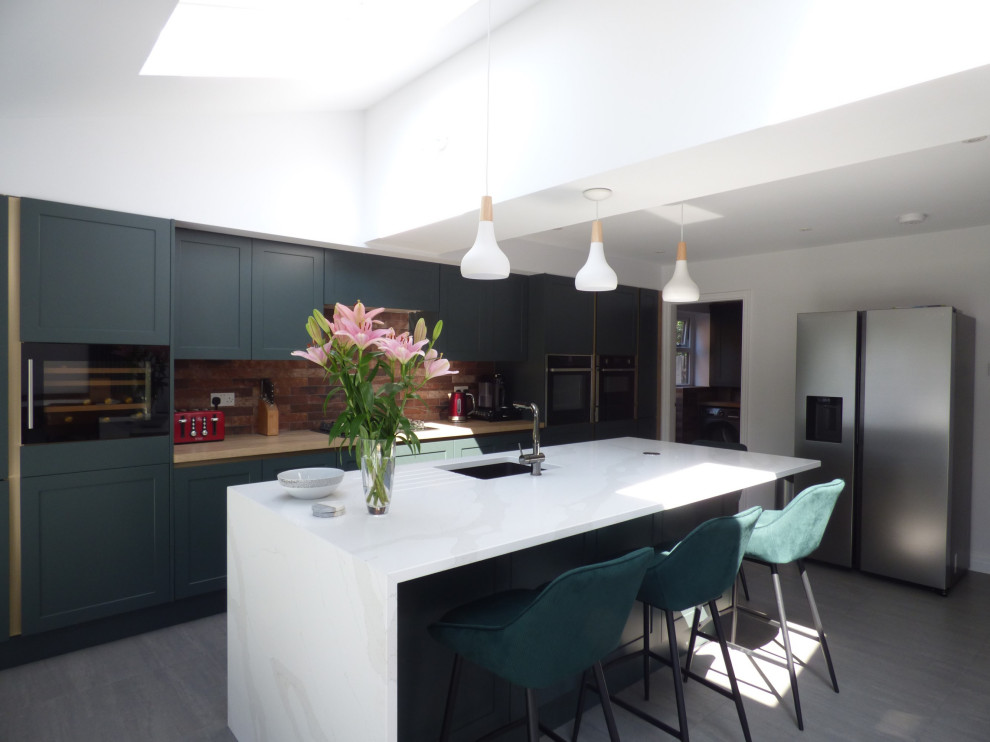 This is an example of a mid-sized modern single-wall open plan kitchen in Other with an integrated sink, shaker cabinets, green cabinets, quartzite benchtops, brick splashback, panelled appliances, with island and white benchtop.