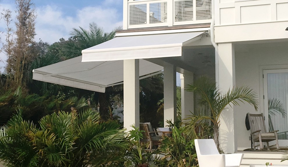 Mid-sized beach style backyard patio in Jacksonville with concrete pavers and an awning.