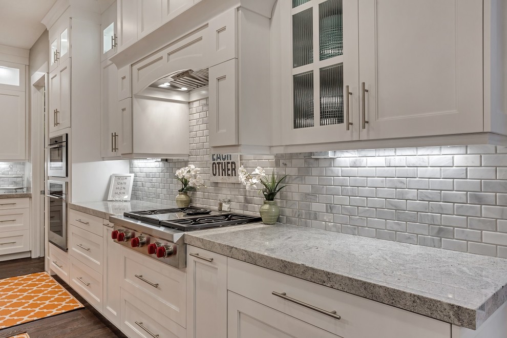 This is an example of a large arts and crafts open plan kitchen in Salt Lake City with an undermount sink, recessed-panel cabinets, white cabinets, granite benchtops, multi-coloured splashback, stone tile splashback, stainless steel appliances, dark hardwood floors, with island and brown floor.