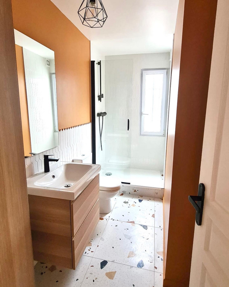 Идея дизайна: узкая и длинная главная ванная комната среднего размера в стиле модернизм с светлыми деревянными фасадами, открытым душем, унитазом-моноблоком, белой плиткой, оранжевыми стенами, полом из терраццо, разноцветным полом, душем с распашными дверями, тумбой под одну раковину и подвесной тумбой