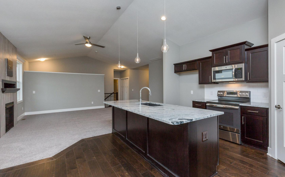 Inspiration for a large transitional dark wood floor and brown floor eat-in kitchen remodel with an undermount sink, shaker cabinets, dark wood cabinets, granite countertops, white backsplash, subway tile backsplash, stainless steel appliances, an island and multicolored countertops