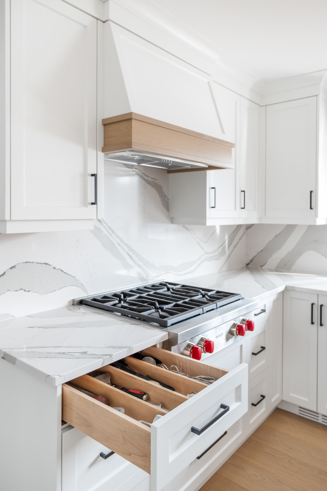 Eat-in kitchen - mid-sized transitional u-shaped light wood floor eat-in kitchen idea in Toronto with an undermount sink, shaker cabinets, white cabinets, quartz countertops, white backsplash, quartz backsplash, stainless steel appliances, an island and white countertops