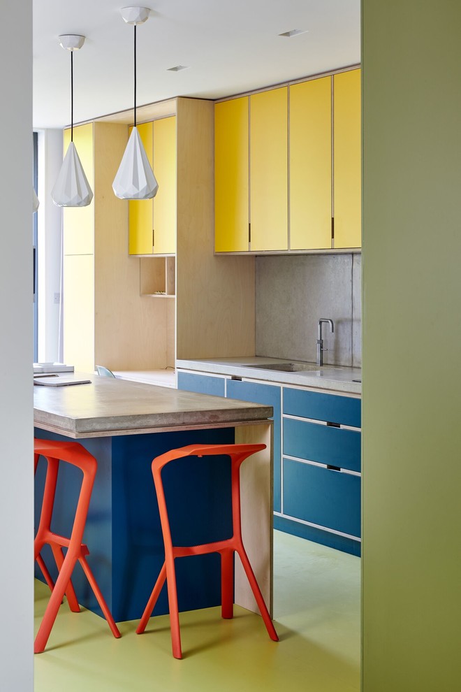 Design ideas for a mid-sized contemporary l-shaped eat-in kitchen in London with an undermount sink, flat-panel cabinets, yellow cabinets, concrete benchtops, grey splashback, cement tile splashback, black appliances and with island.