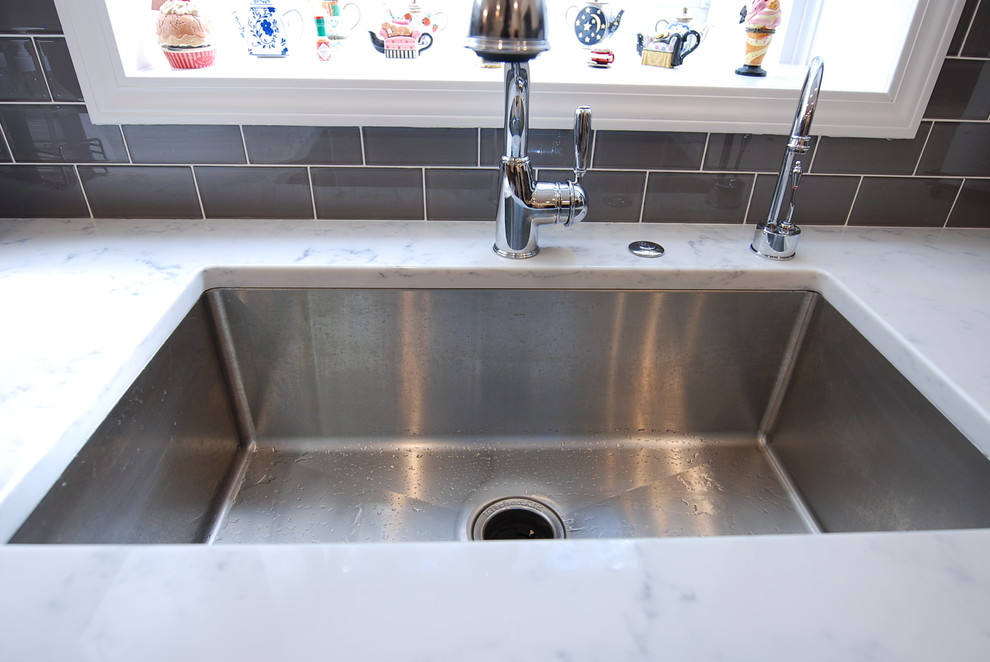 Mid-sized transitional u-shaped light wood floor eat-in kitchen photo in Chicago with a single-bowl sink, recessed-panel cabinets, white cabinets, quartzite countertops, gray backsplash, porcelain backsplash, stainless steel appliances and an island