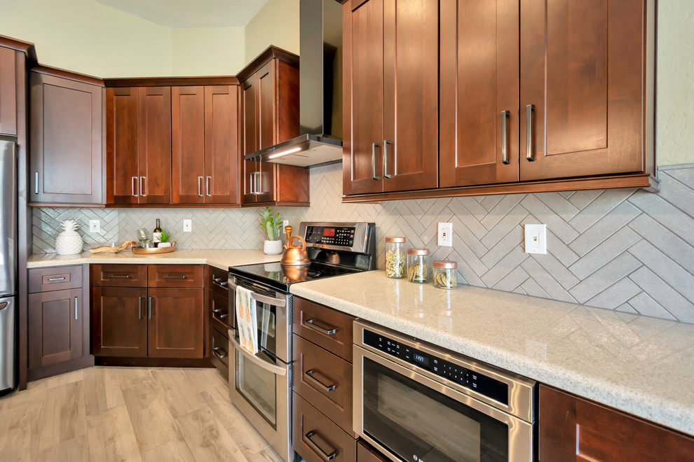 Open concept kitchen - mid-sized transitional l-shaped porcelain tile and brown floor open concept kitchen idea in Phoenix with a single-bowl sink, shaker cabinets, brown cabinets, granite countertops, gray backsplash, brick backsplash, stainless steel appliances, an island and multicolored countertops
