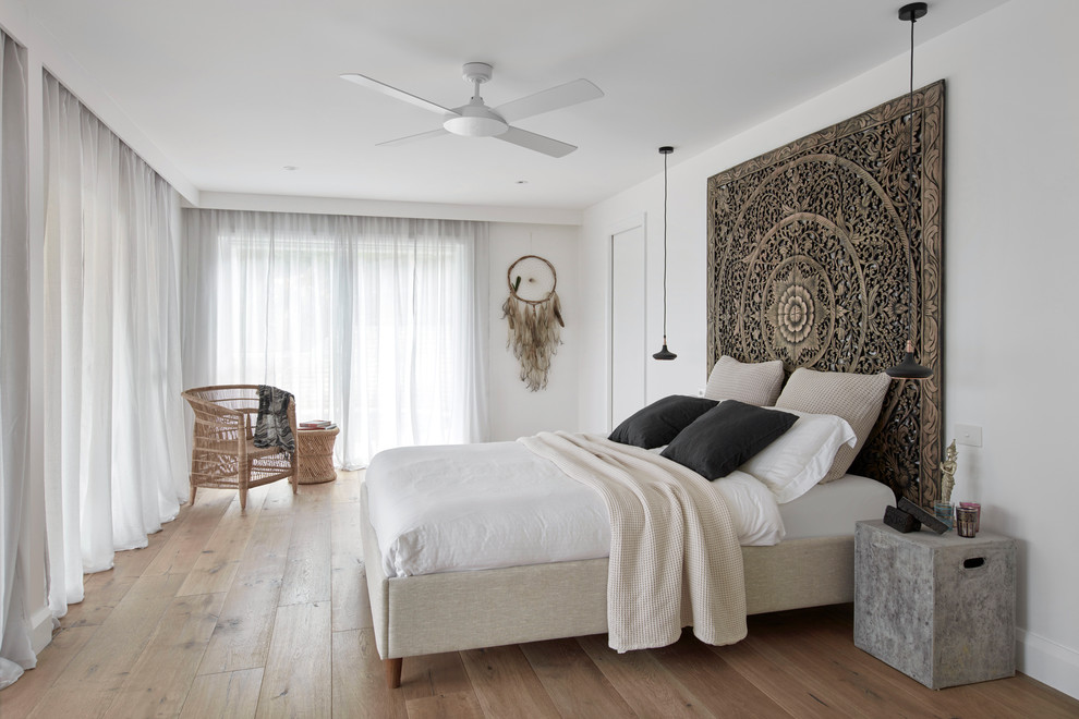 Design ideas for a mid-sized contemporary master bedroom in Sydney with white walls, medium hardwood floors and brown floor.