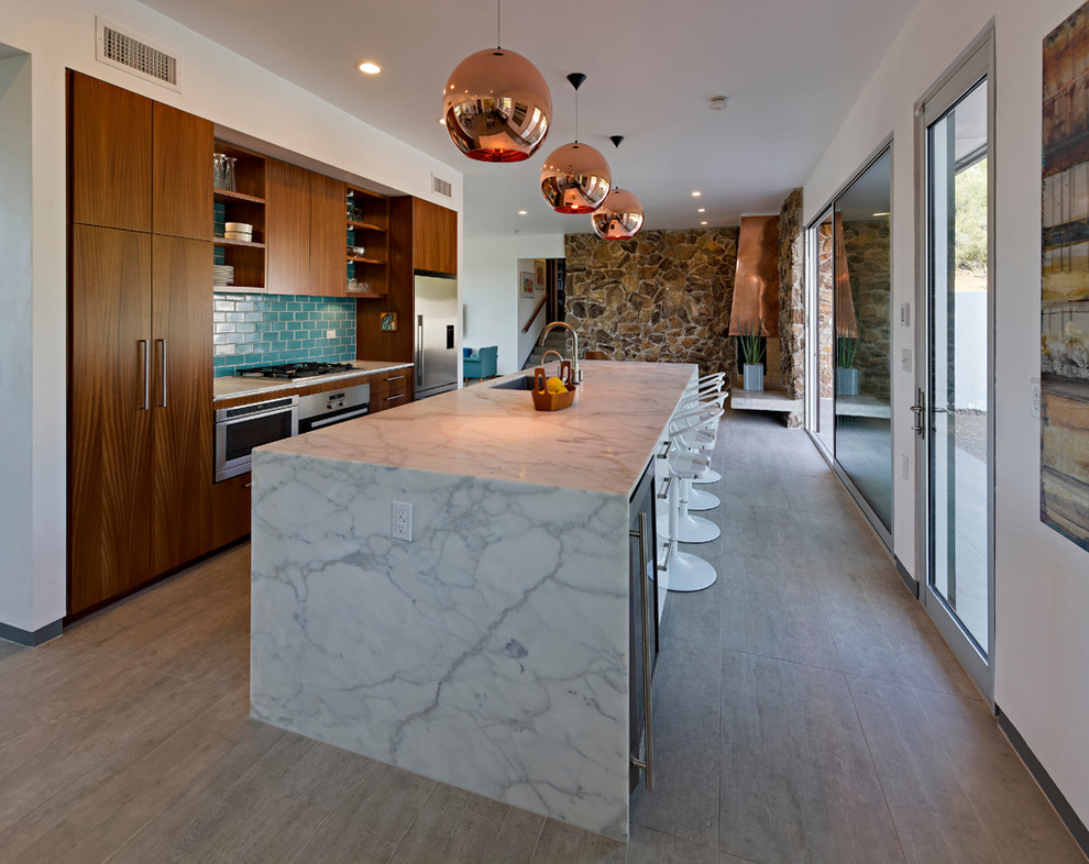 This is an example of a midcentury open plan kitchen in Phoenix with an undermount sink, flat-panel cabinets, medium wood cabinets, marble benchtops, blue splashback, ceramic splashback, stainless steel appliances, porcelain floors and with island.