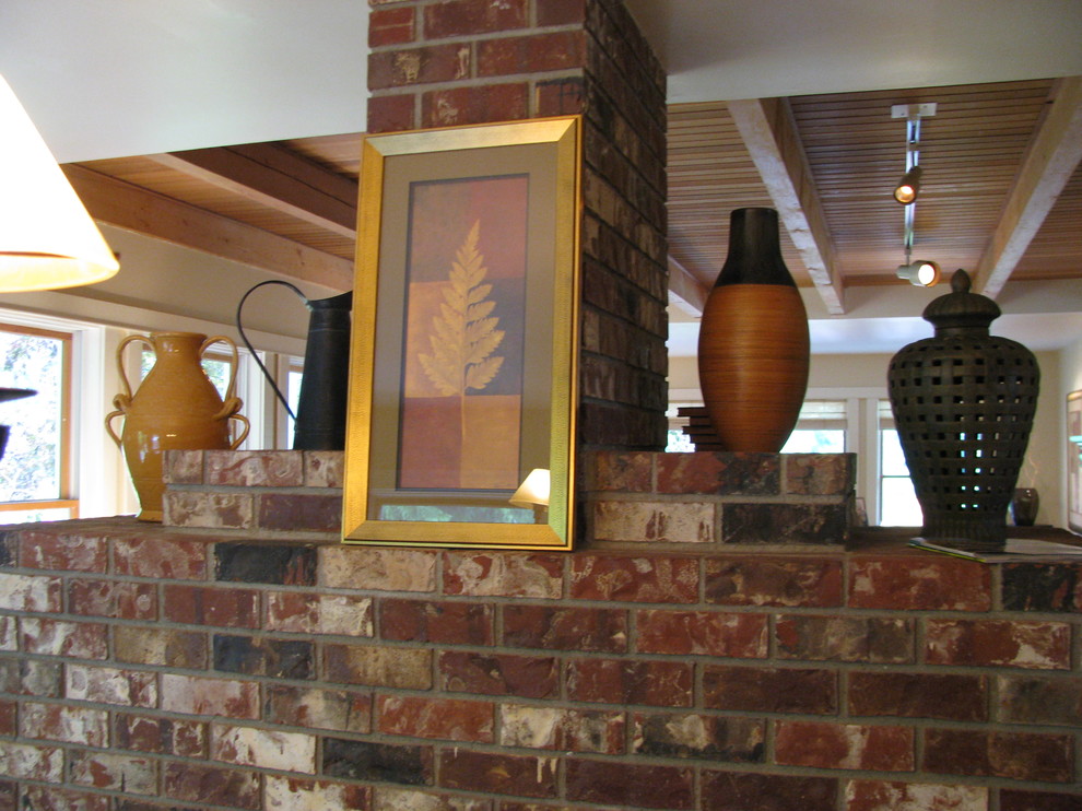 Photo of a mid-sized transitional open plan dining in Seattle with yellow walls, light hardwood floors, a two-sided fireplace and a brick fireplace surround.