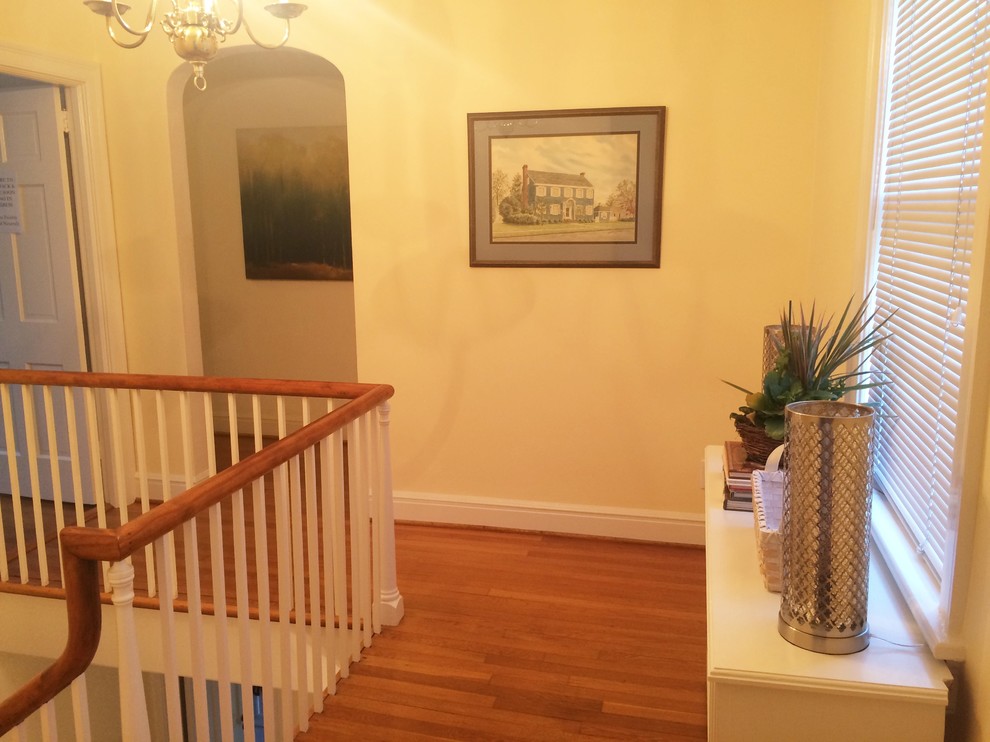Large transitional medium tone wood floor hallway photo with yellow walls