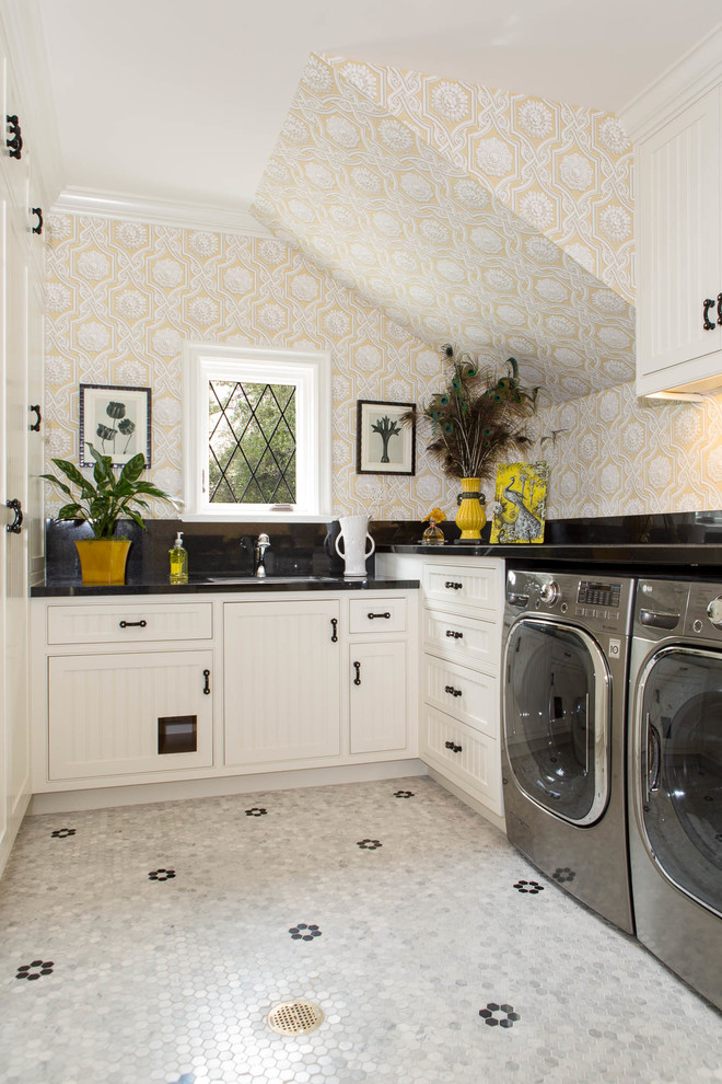 Traditional l-shaped laundry room in Los Angeles with recessed-panel cabinets, white cabinets, a side-by-side washer and dryer, black benchtop and beige walls.