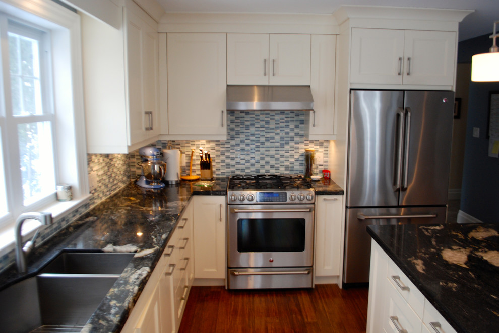 Kitchen - small transitional l-shaped medium tone wood floor and brown floor kitchen idea in Toronto with an undermount sink, recessed-panel cabinets, white cabinets, blue backsplash, matchstick tile backsplash, stainless steel appliances and an island